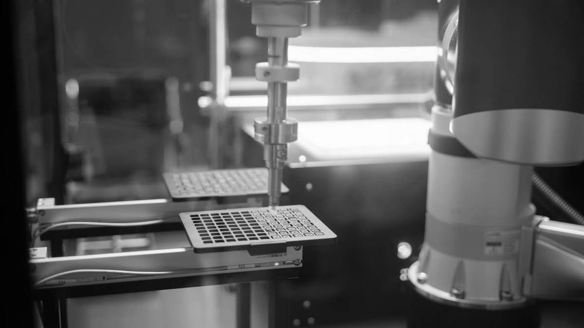 A robotic arm handling a microplate on an automated laboratory bench